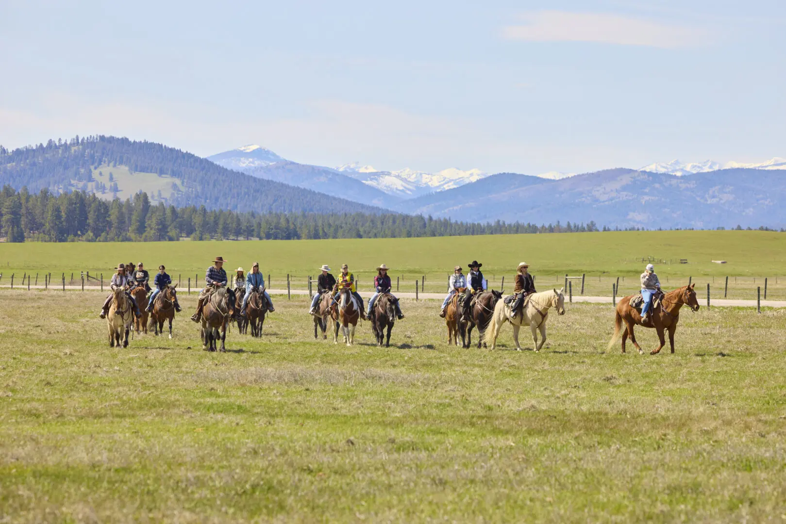 Group of cowgirls riding on a field with mountains behind them.