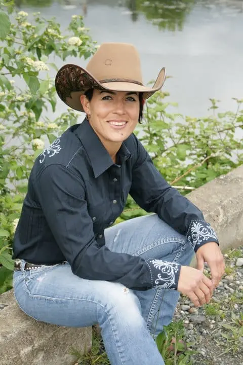 Image of women sitting down decked out in cowgirl riding gear.