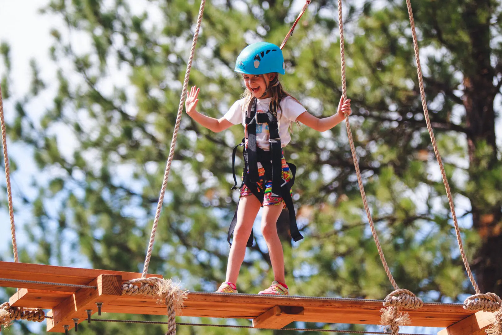 Girl walking along an outdoor ropes course.