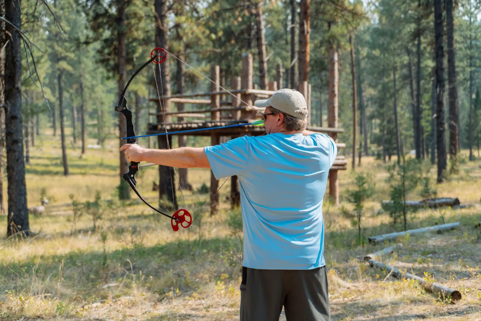 Man shooting a bow and arrow in a forest.