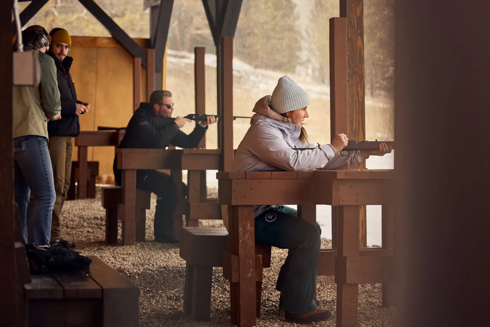 Woman and man shooting rifles in a shooting range.