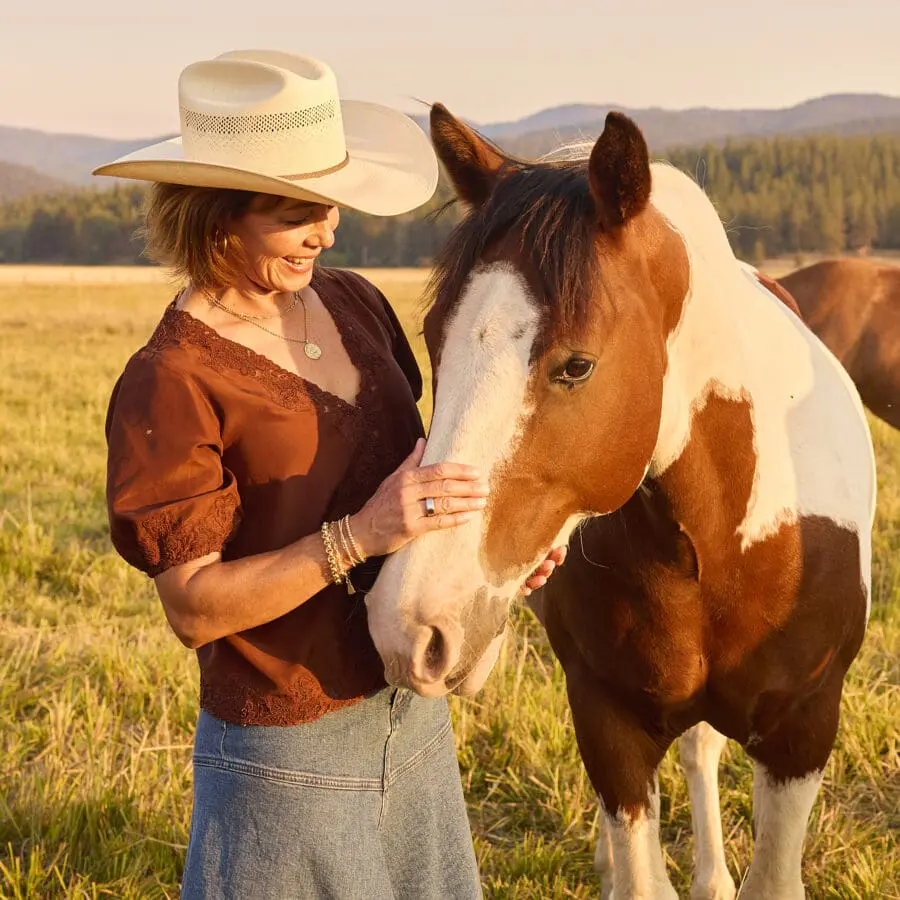 Woman petting a horse in an open field.
