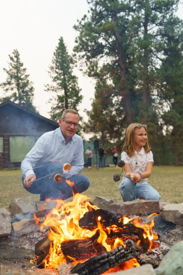 Girl and her father roasting more by the fire.
