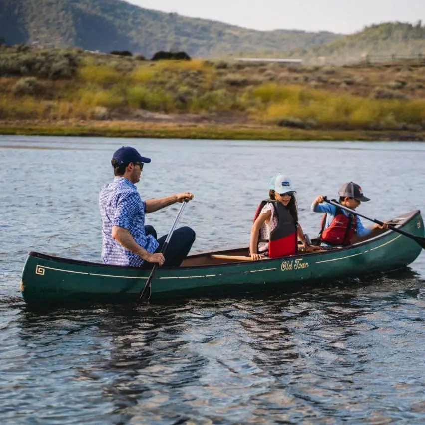 A family paddling through a mountain river in a canoe