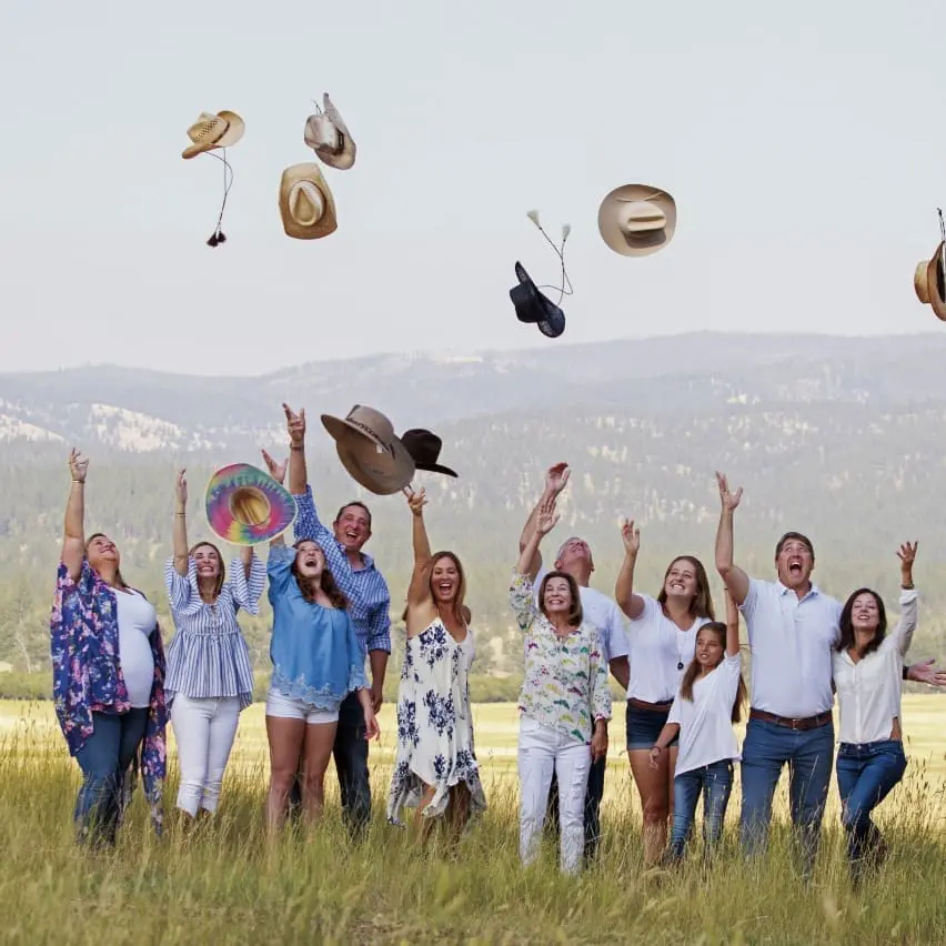 Multi-generational family throwing their cowboy hats in the air