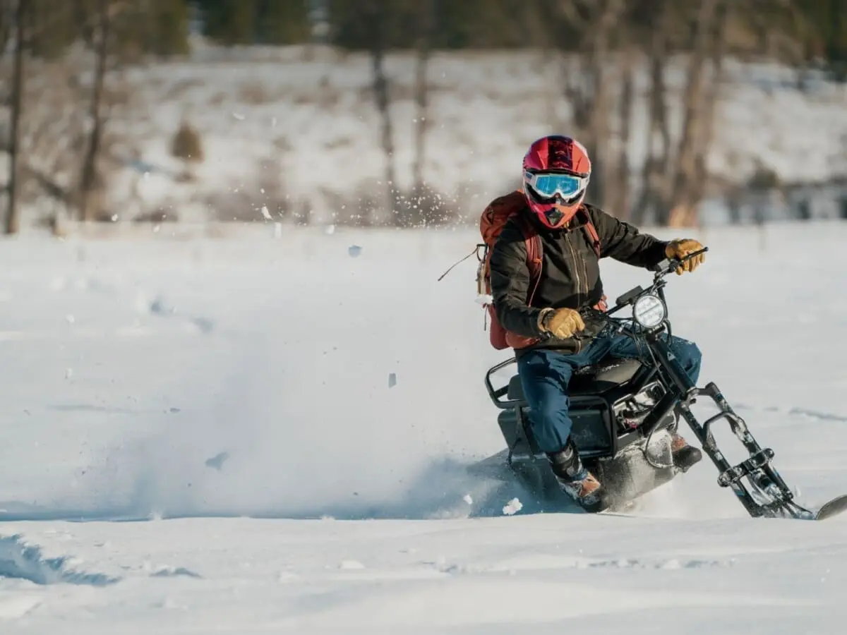 Person quickly riding a moonbike (electric snowbike) through the winter snow