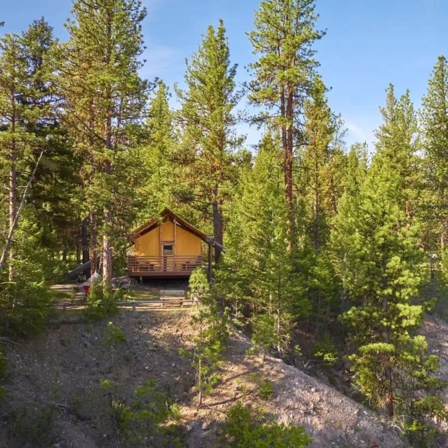 Wide view of a glamping tent on a cliff beside the Blackfoot River