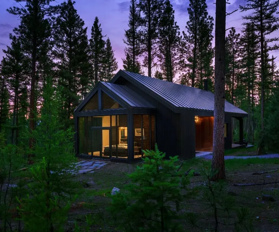 Outside view of Light Haus at dusk in the forest, a modern black haus with windowed walls