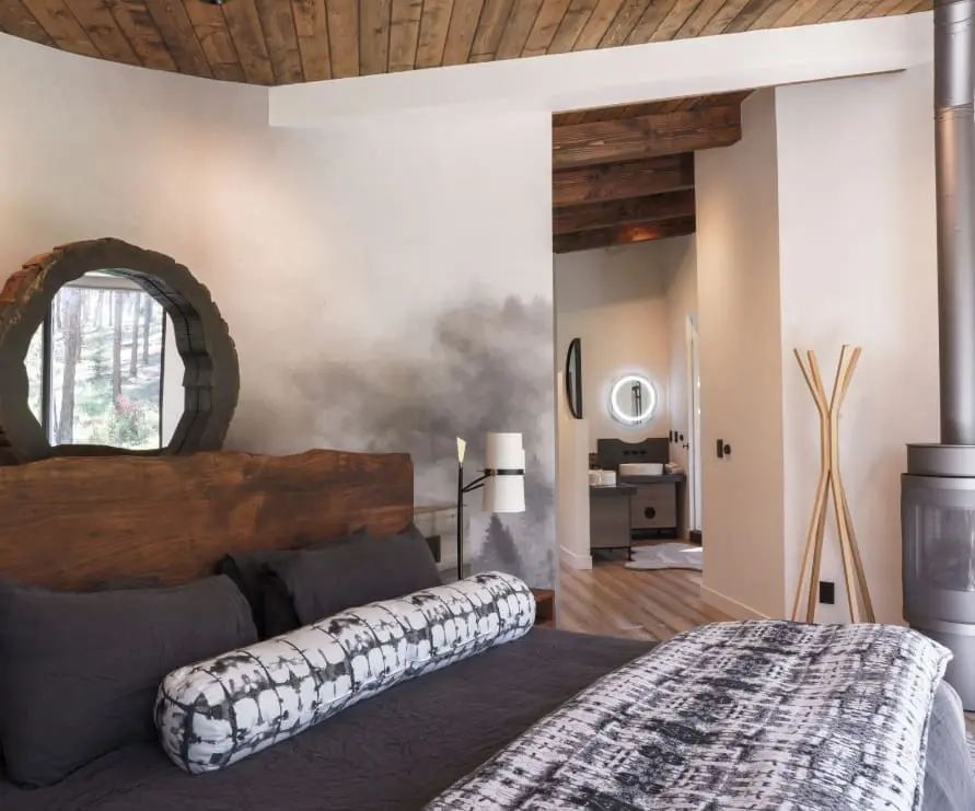 Inside view of the bedroom in Round Haus at Green O, a king size bed with a hand painted mountain mural on the wall behind