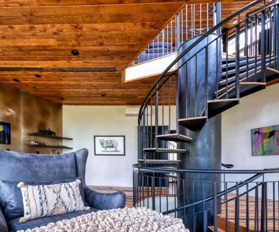 Inside view of Tree Haus showcasing the living room with a leather chair and spiral metal staircase through the middle