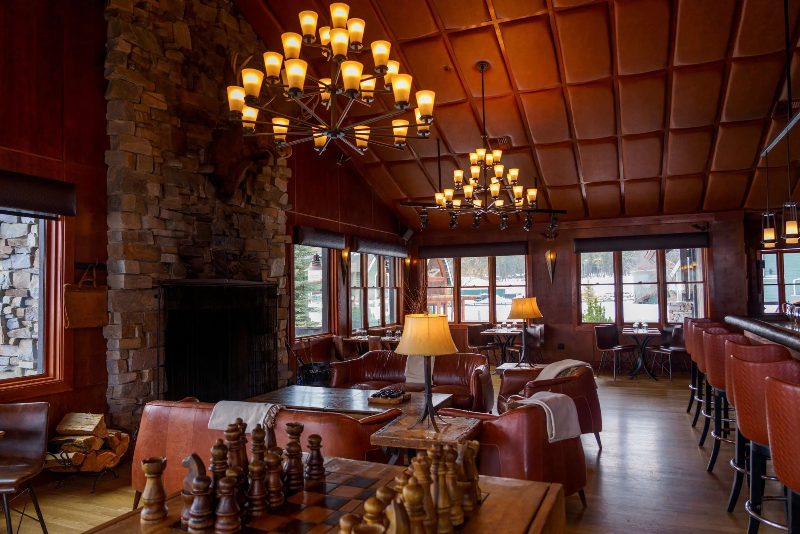 Indoor view of the bar Tank at Paws Up Montana, a modern twist on a leather western look, with dark leather seating and a stone fireplace