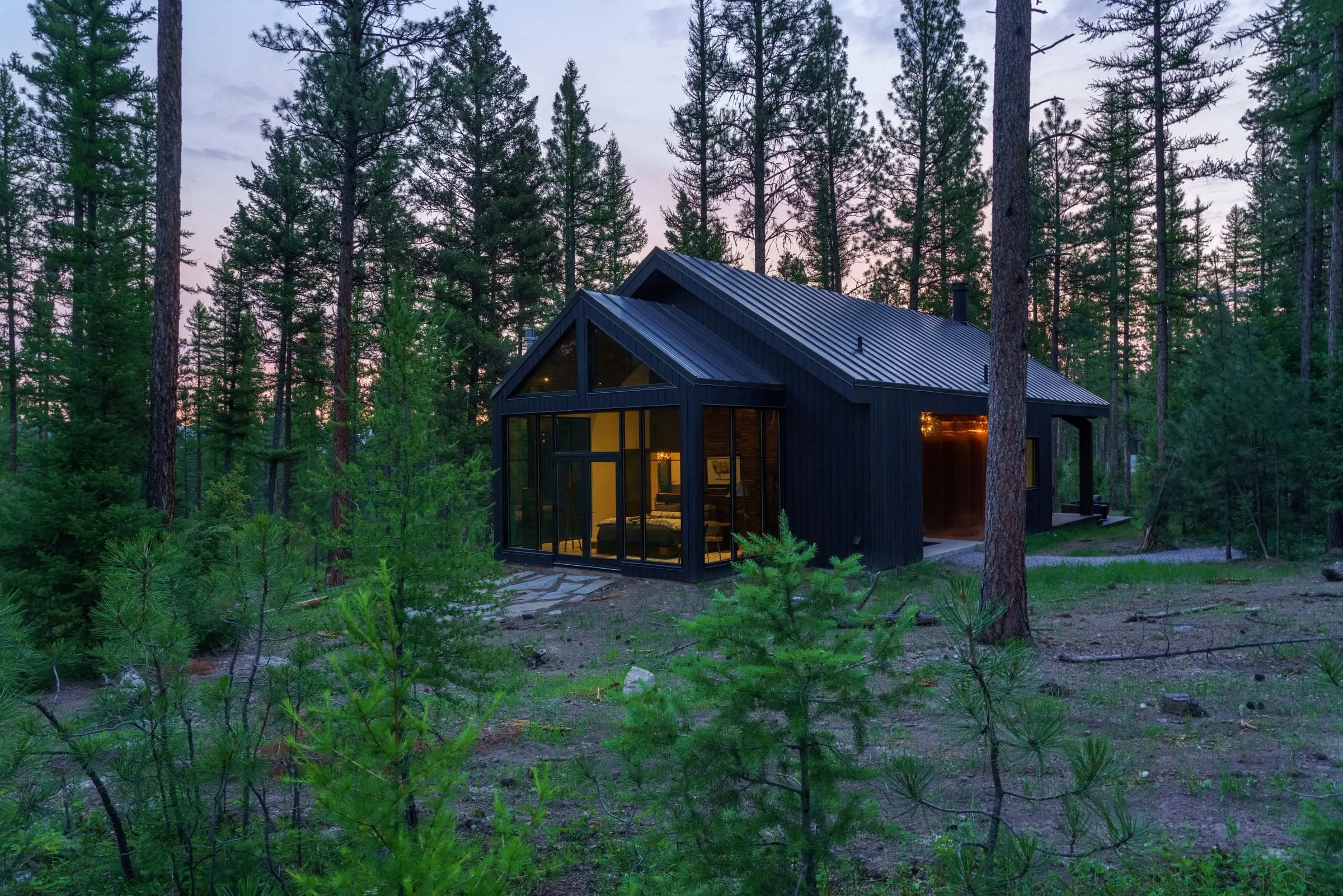 Exterior of modern cabin with window walls in the forest