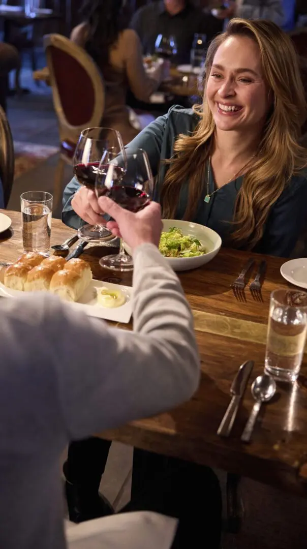 Couple sitting at a table eating dinner and drinking wine.