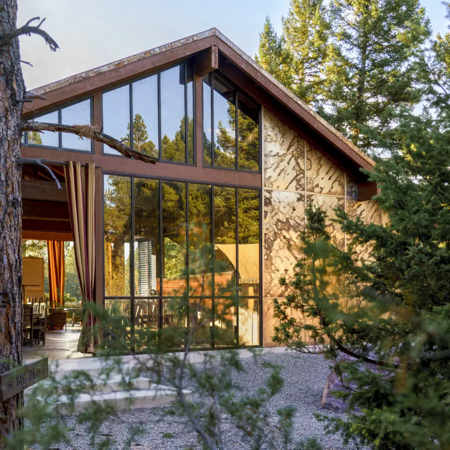 Large glass and stone building surrounded by trees.