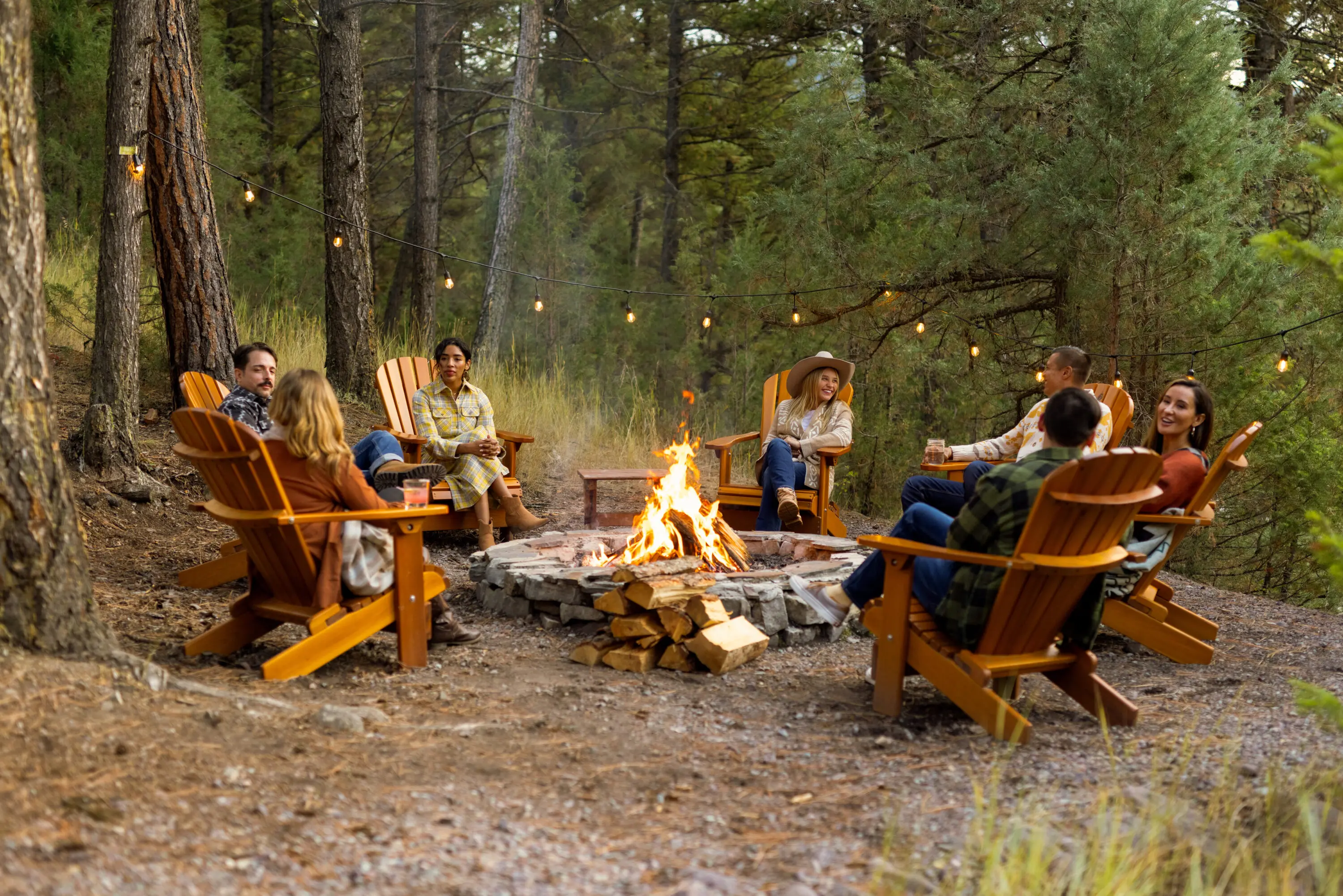 Group of individuals sitting around a fire outside.