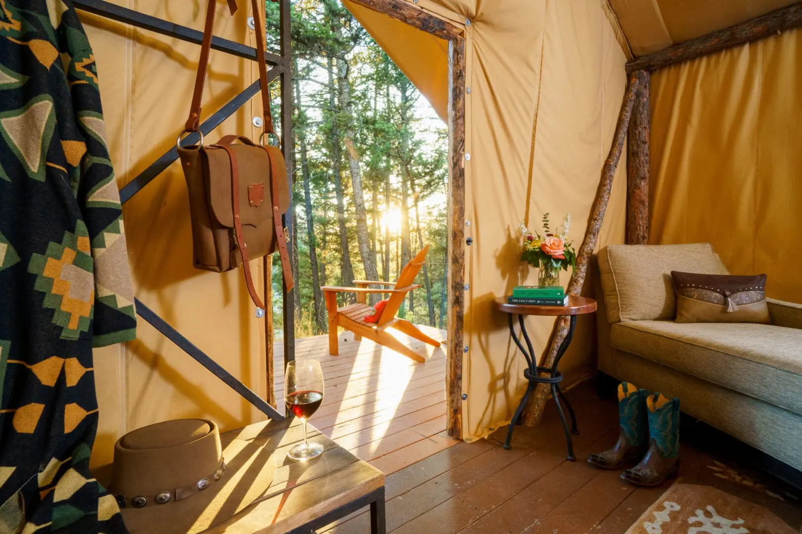 Inside of a western themed glamping tent with the door open overlooking trees and a chair on a porch.