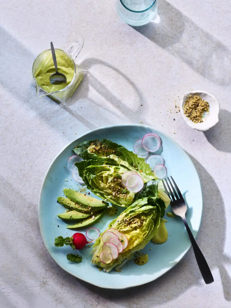 A plate with arranged lets and avocados with a drink on the side.