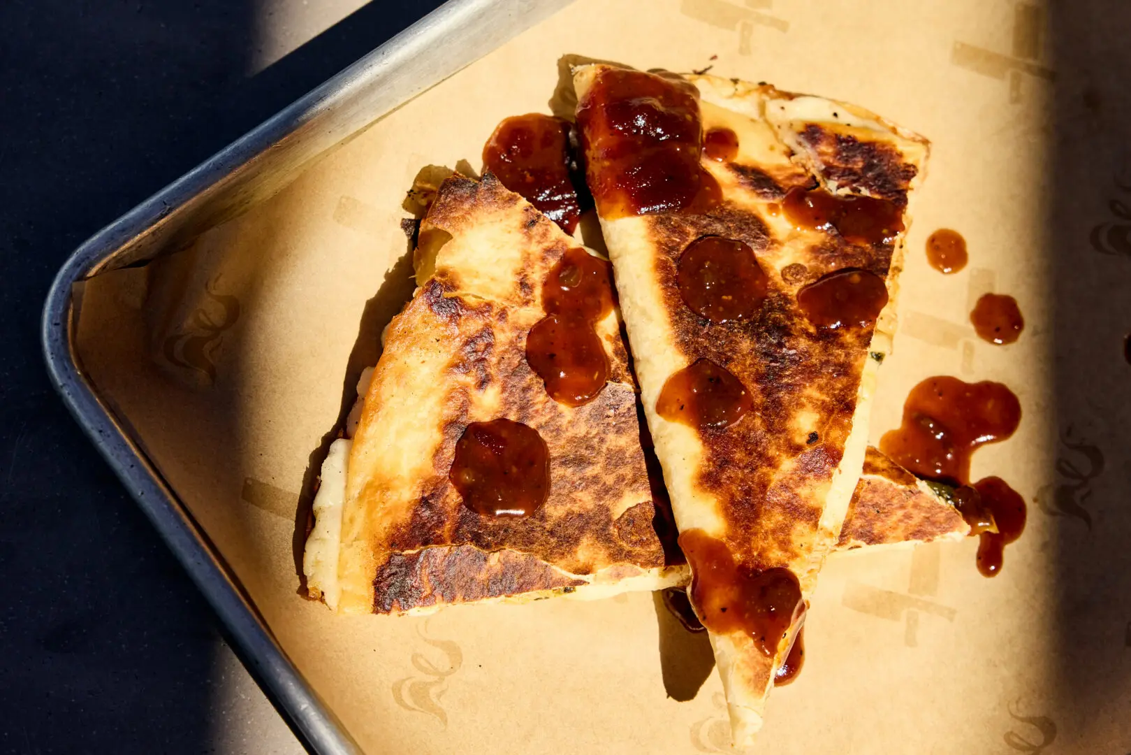 A BBQ quesadilla on a metal tray.