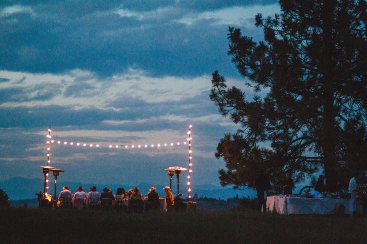 Group of people celebrating at an outdoor table under lights