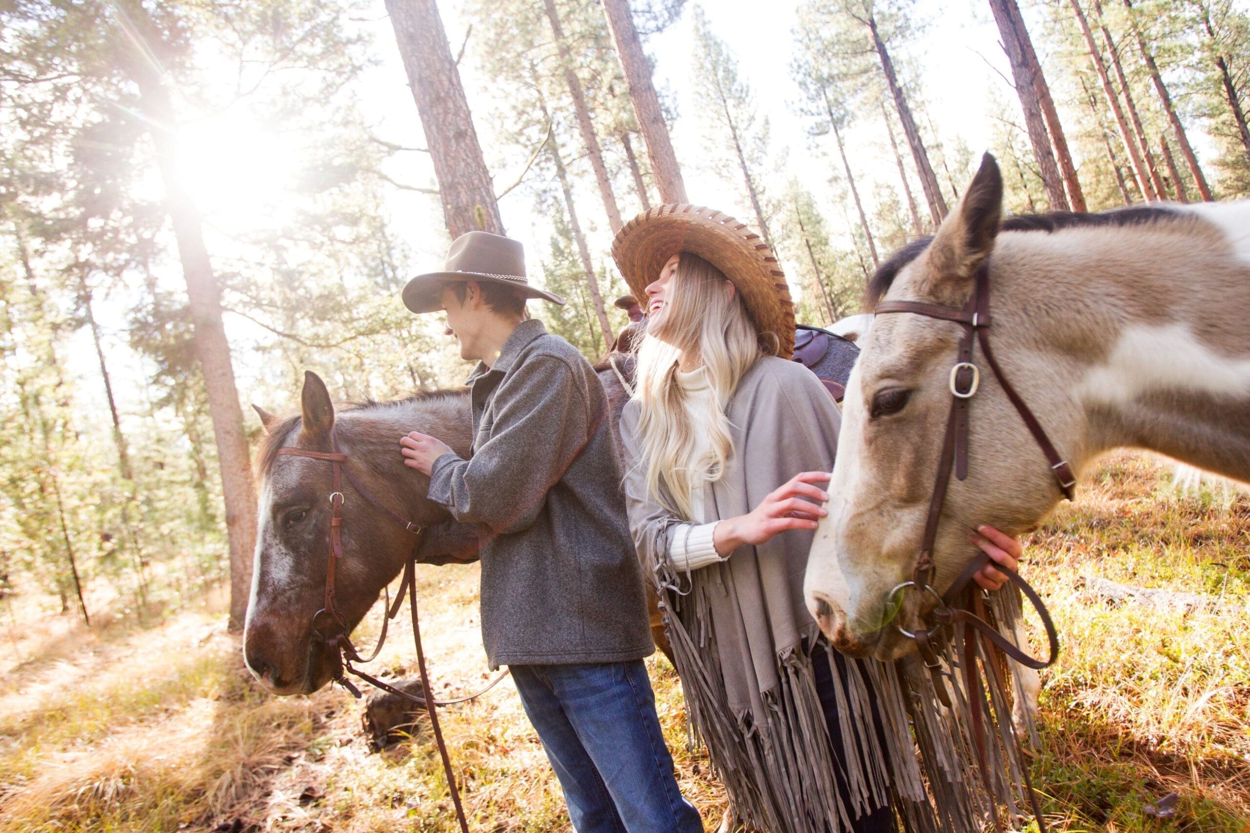 Couple walking two horses through the forest