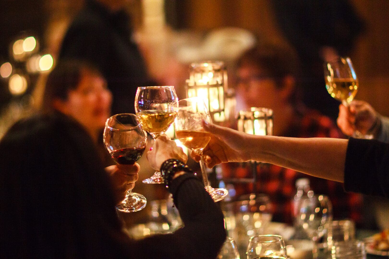 Warm, glowy shot of group of people toasting and clinking glasses of wine.