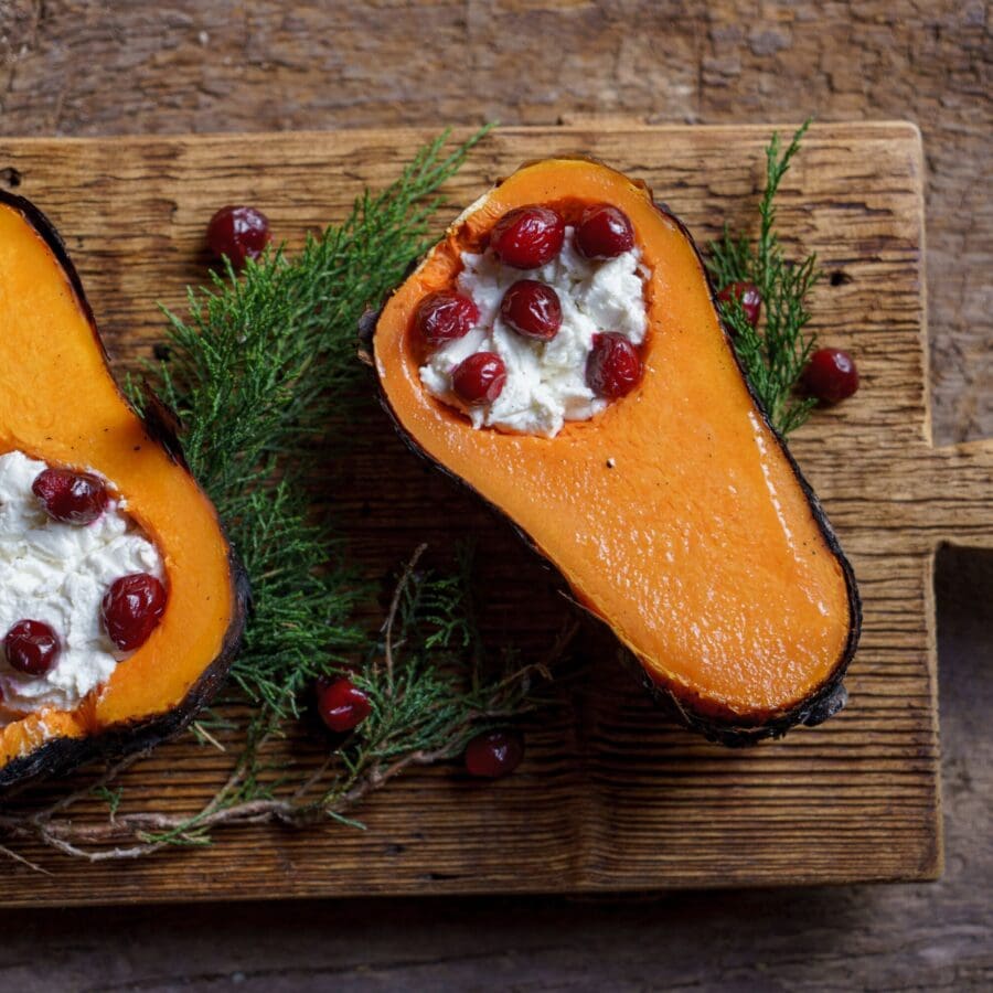 Decorative cooked squash with white filling and berries.