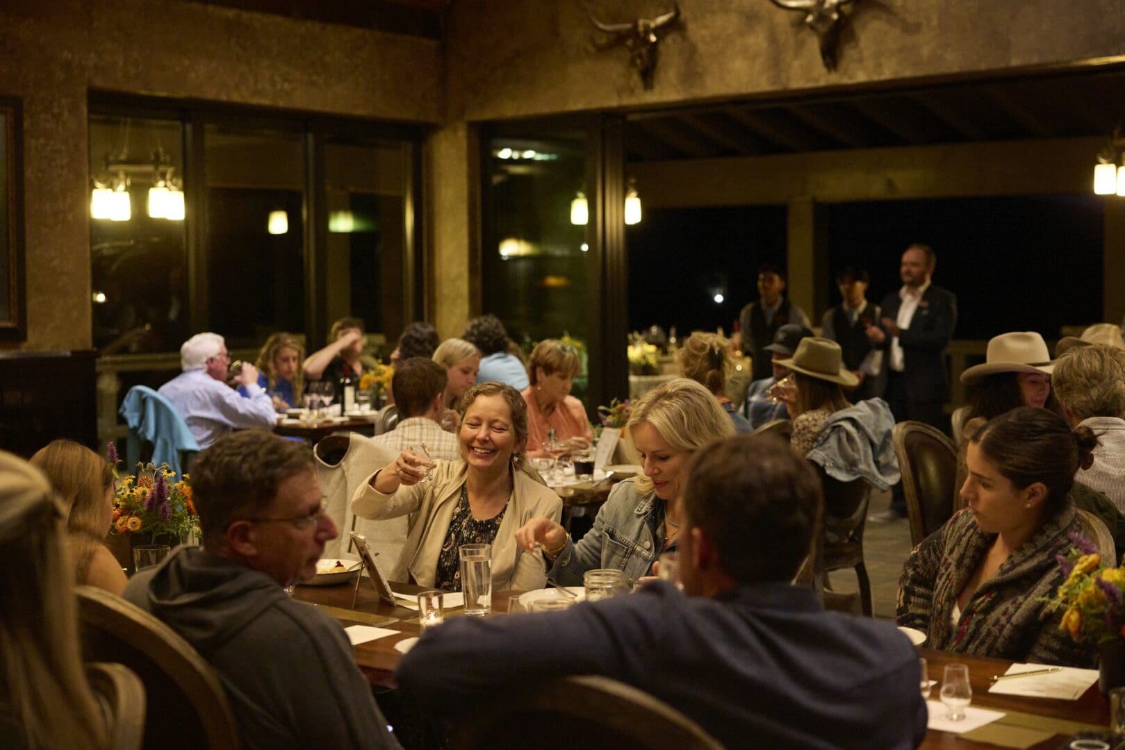 People in a dimly lit restaurant talking and smiling.