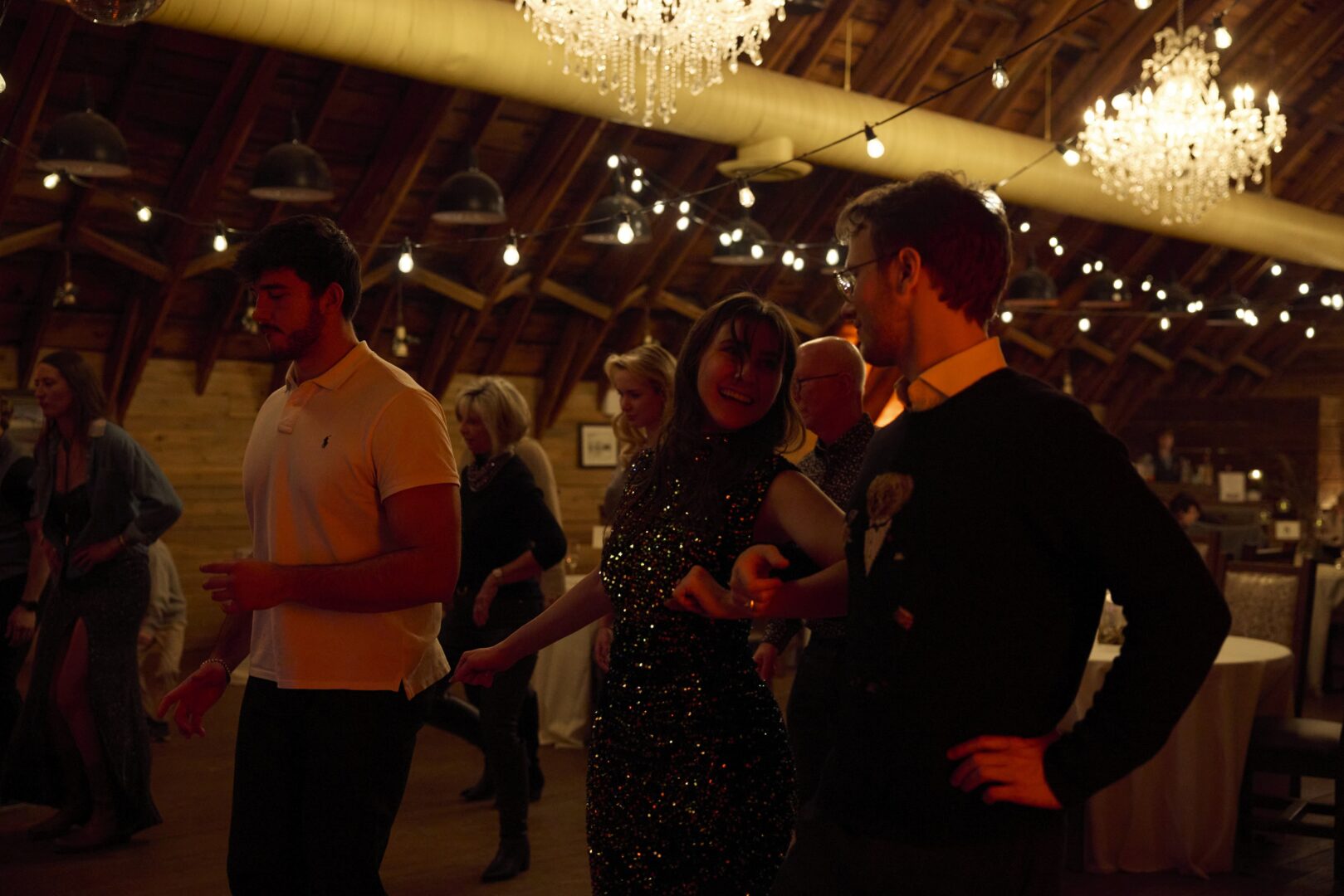 A group of people gathered in a warmly lit indoor space, possibly for a social event.