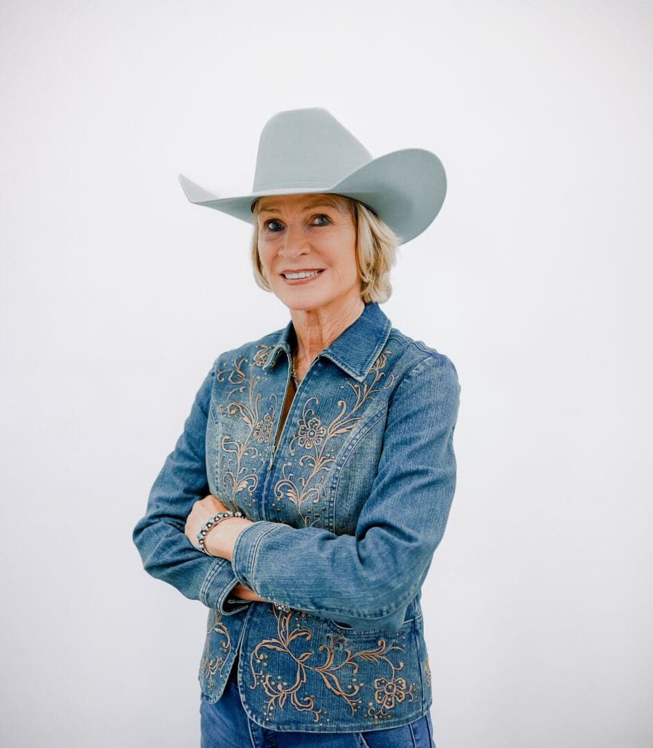 Image of women wearing a denim outfit and white hat with a white background.