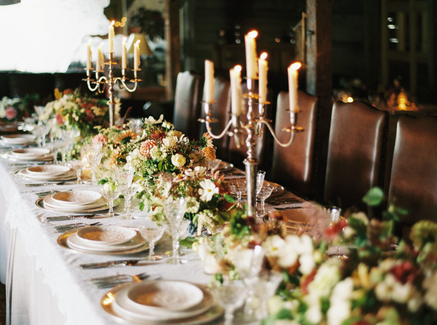 Indoor wedding reception decoration of plates, flowers, and candles.