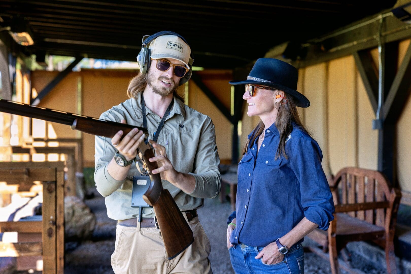 Man showing a woman in a black cowgirl hat a shotgun.