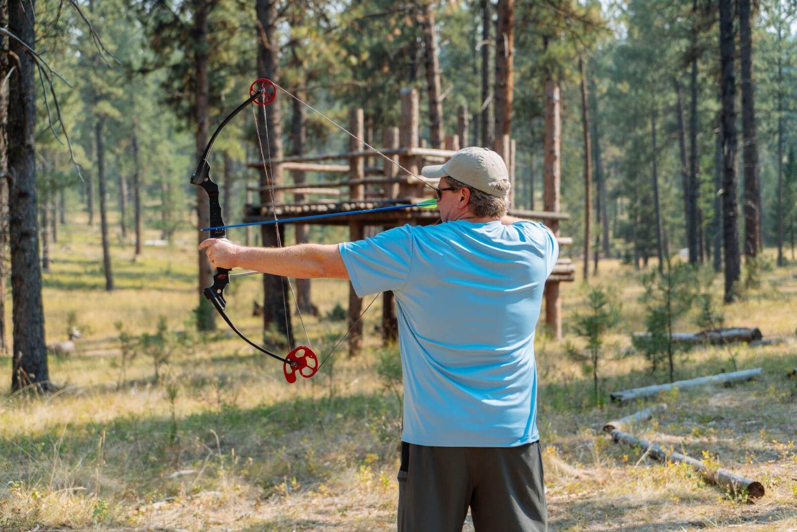 Man shooting a bow and arrow in a forest.