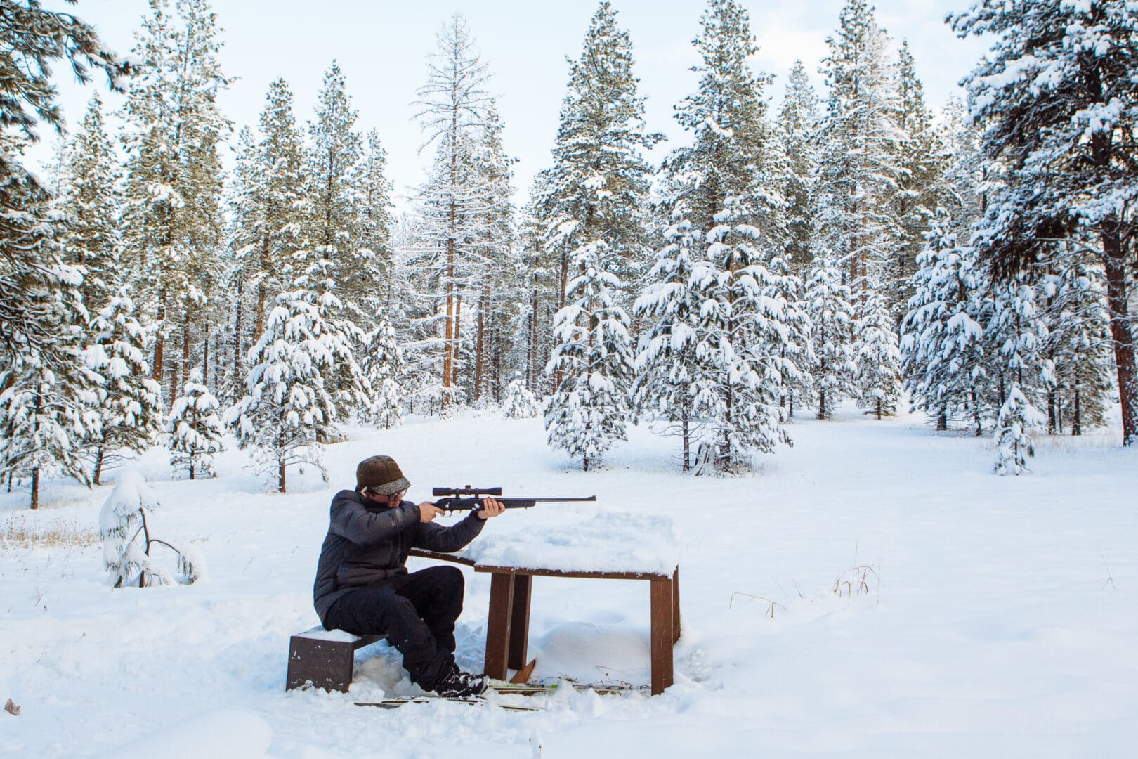 Person practicing shooting in a snowy forest.