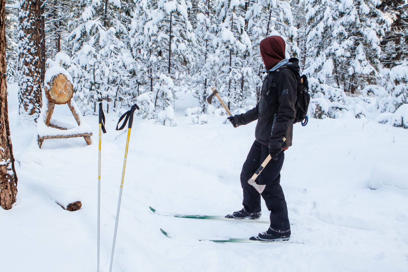 Person cross-country skiing and axe throwing in a snowy forest.