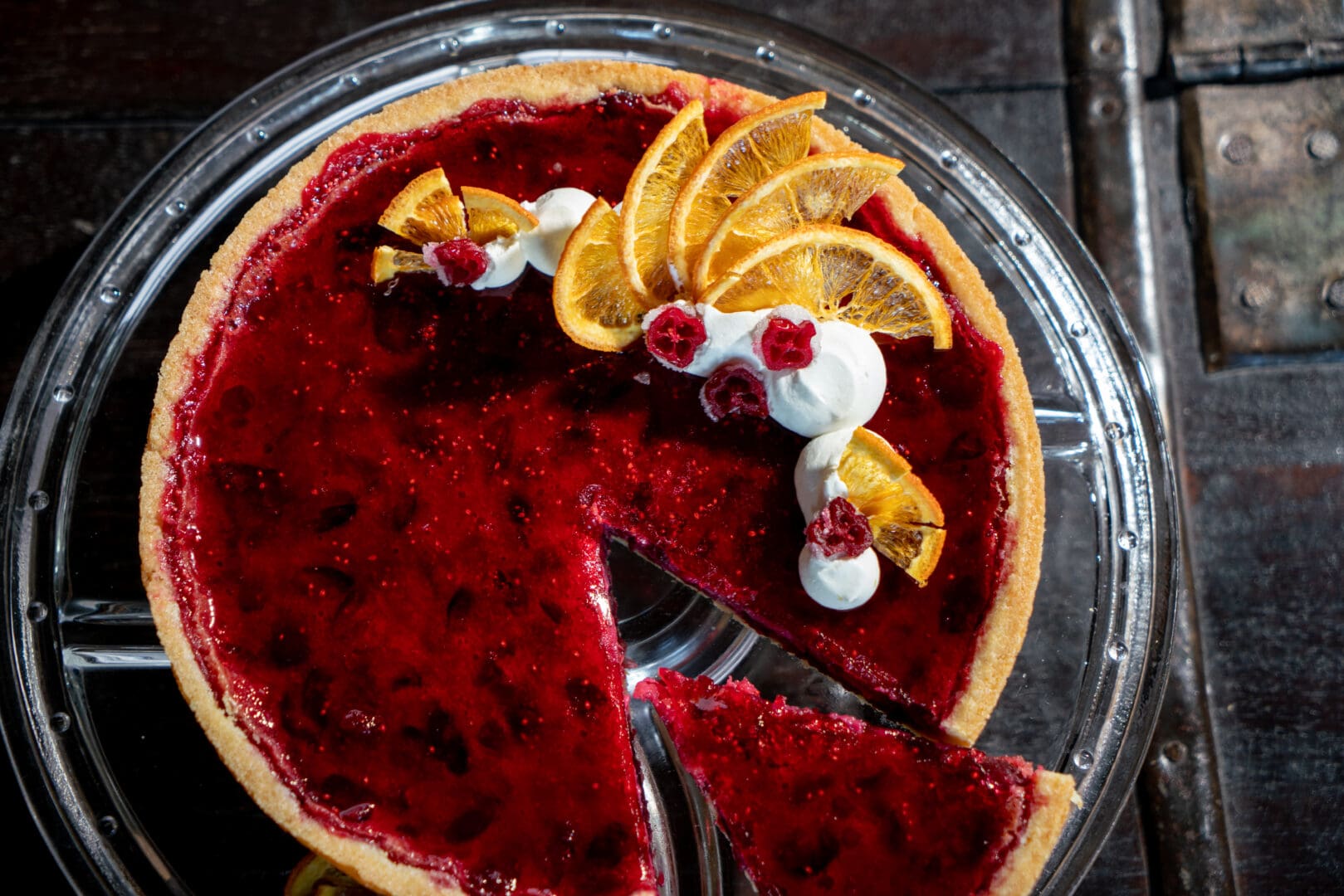 Red, fruit pie with oranges and whipped cream decoration.
