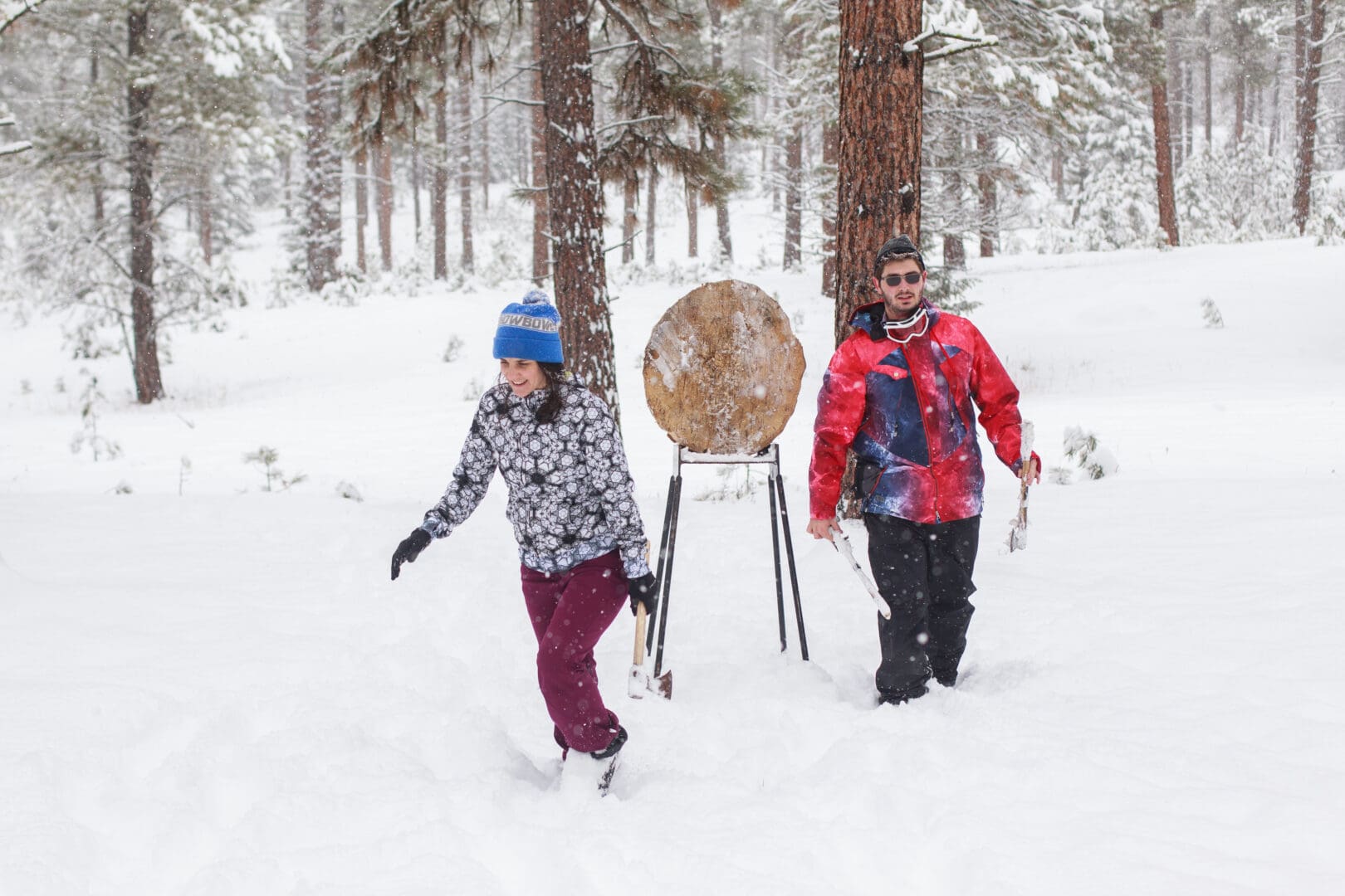 Couple walking back through the snow after throwing axes at a wooden target.