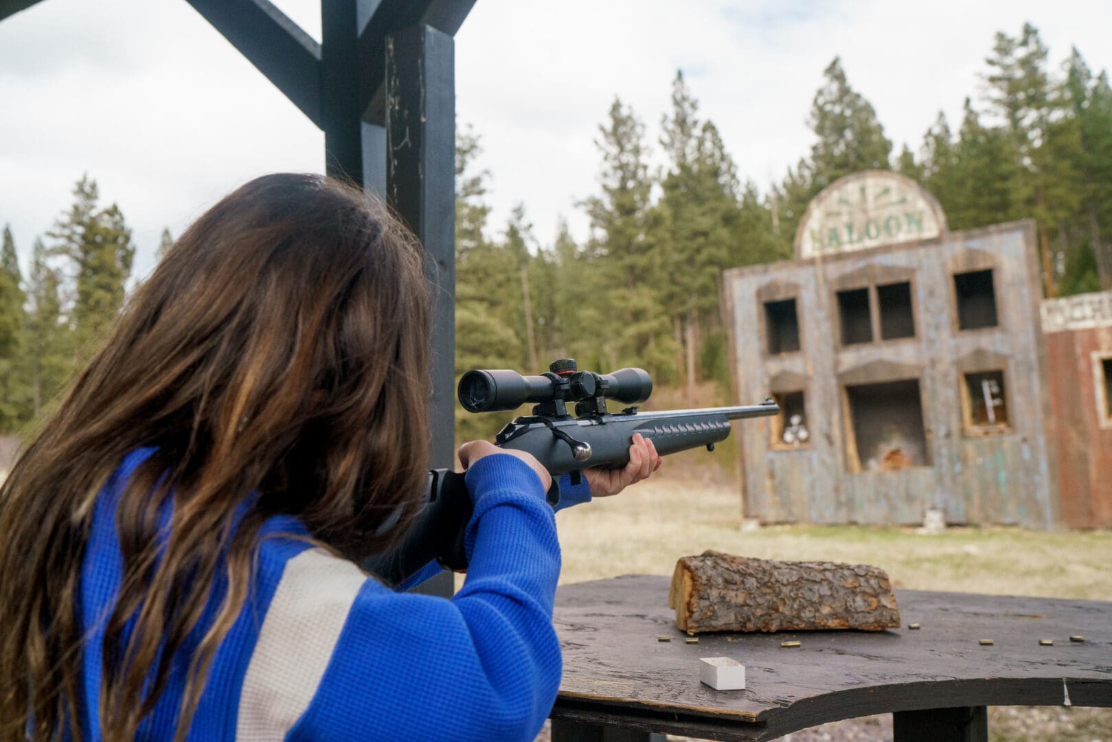 Woman shooting a rifle at a fake western town.