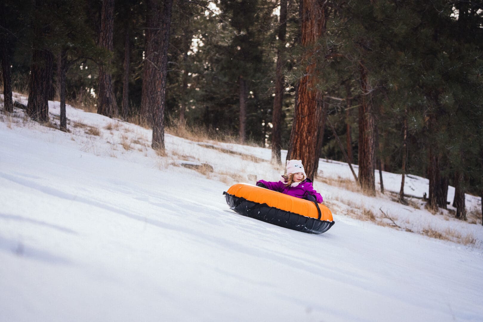 Kid tubing down a snow hill.