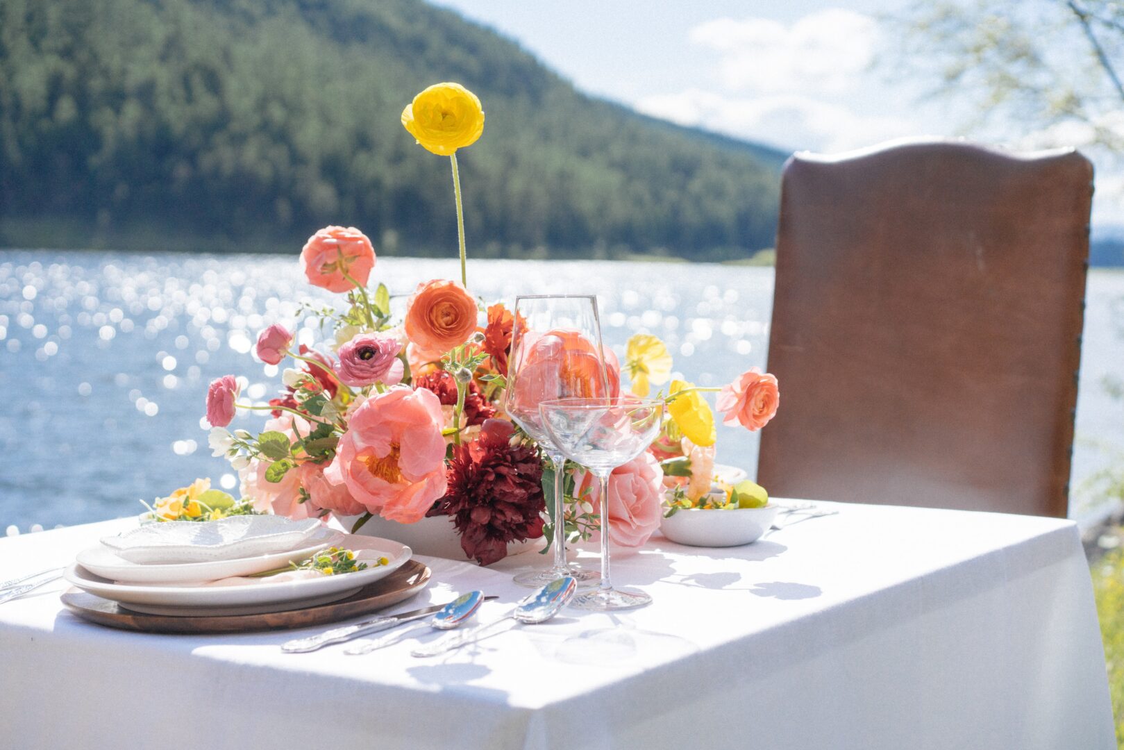 Flowers set on a table with a leather chair and white table.