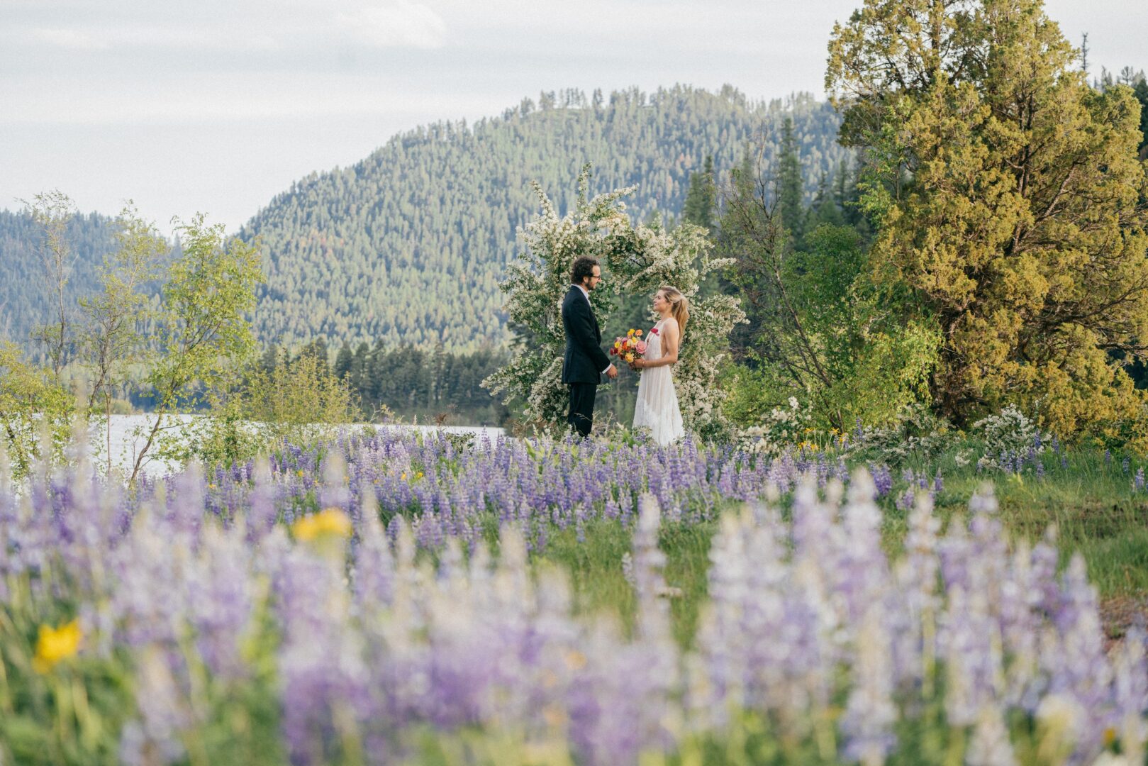 A bride and groom exchanging vows outside in a field of flowers.