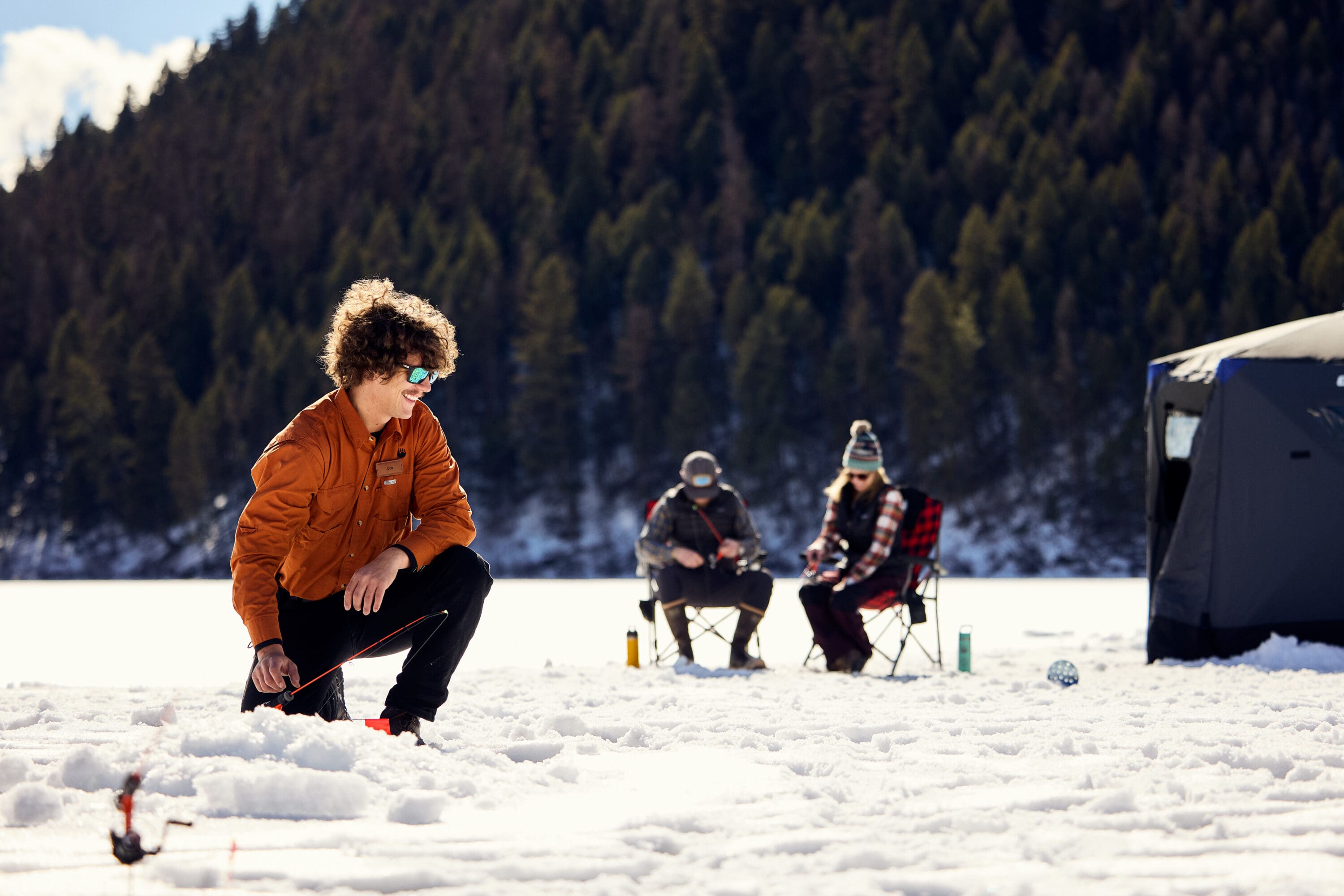 Three people ice fishing.