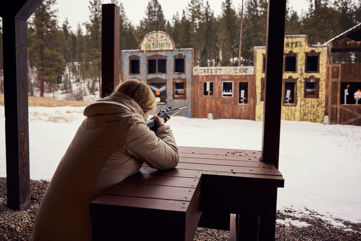 Person shooting rifle at old western wooden town