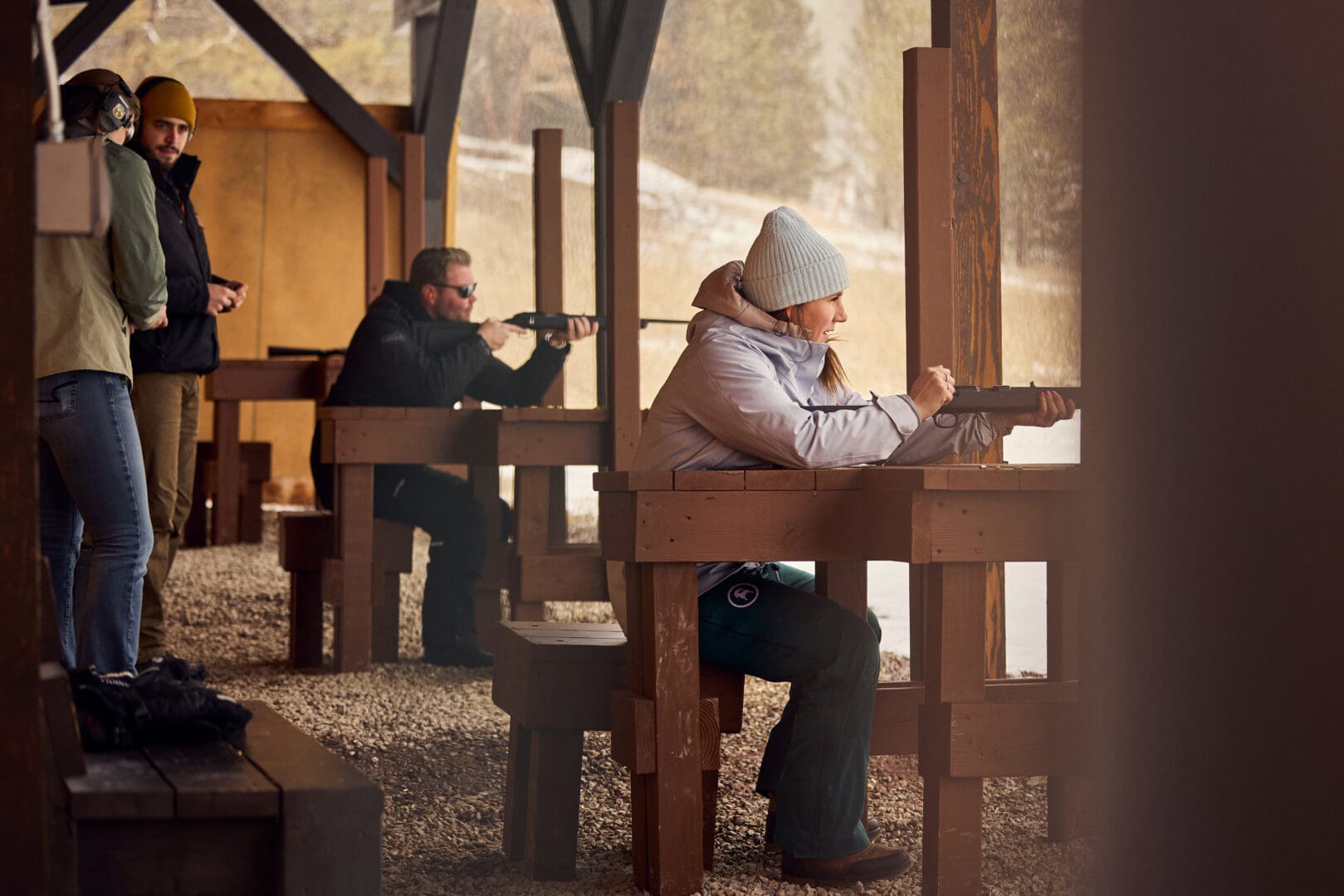 Woman and man shooting rifles in a shooting range.
