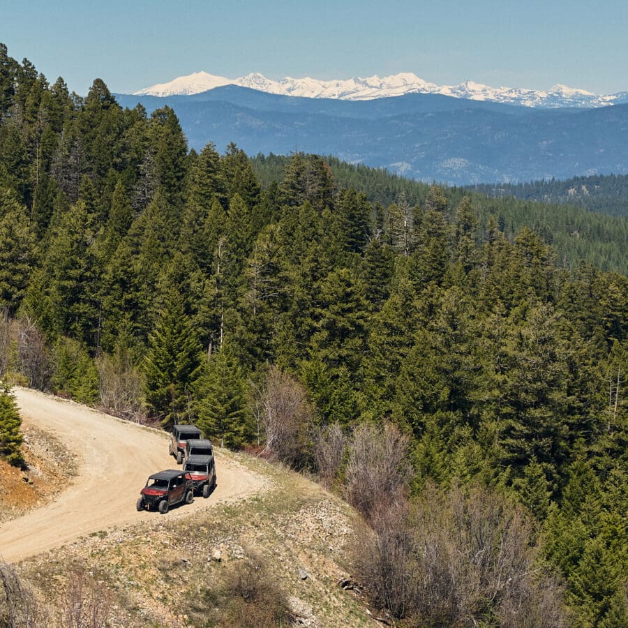 Individuals riding ATV's on a dirt road.