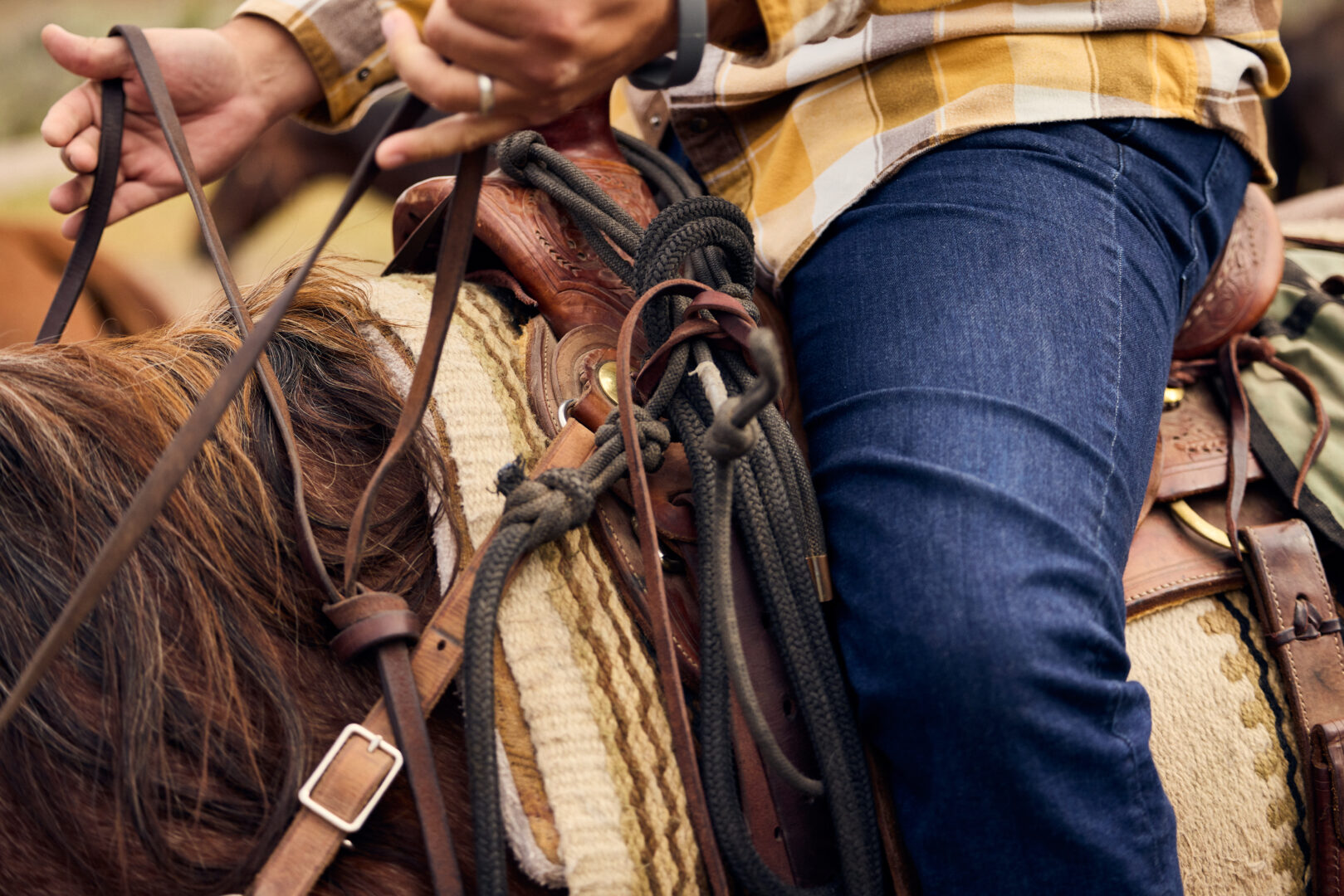 Lower shot of a leg and saddle of someone riding a horse.