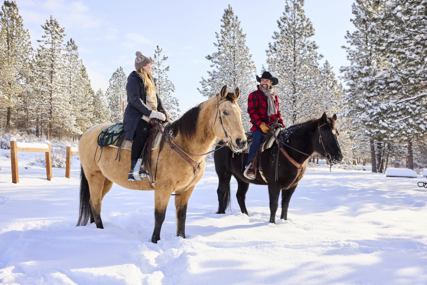 Couple horseback riding in the snow.