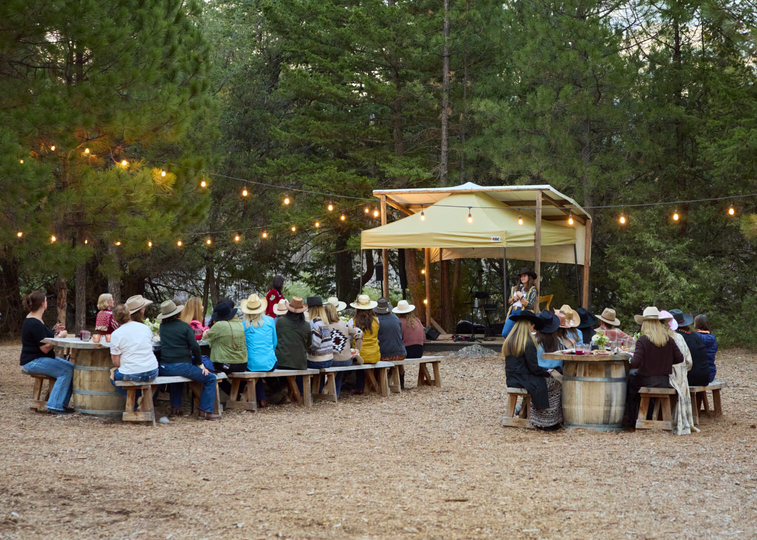 Women sitting together outside with string lights and a tent.