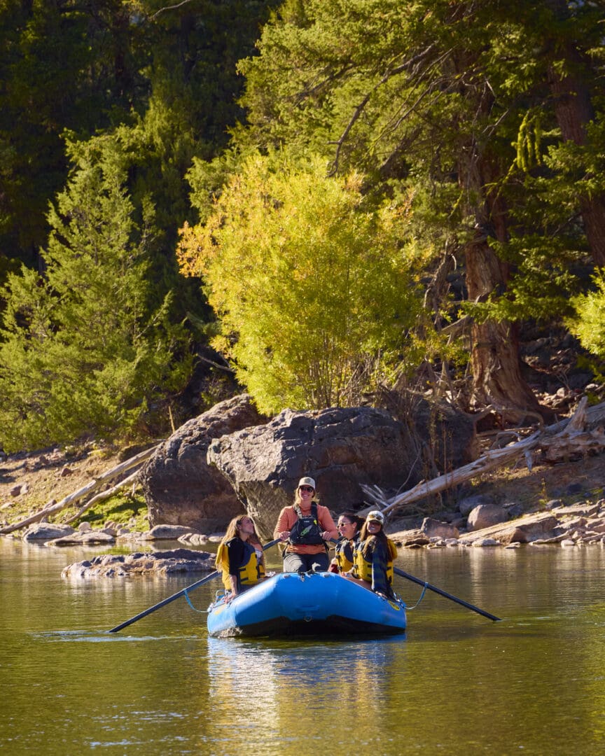 Group of people floating down a river in a blue raft.