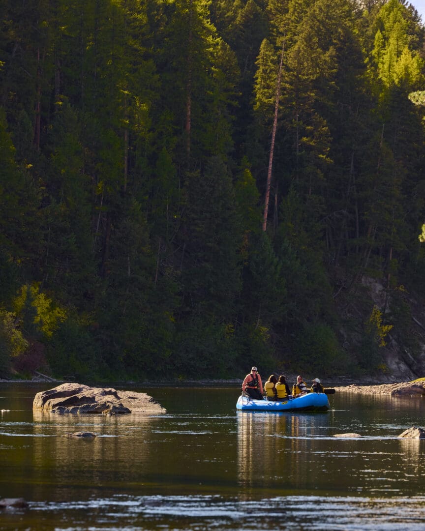 Group of people floating down a river in a blue raft.