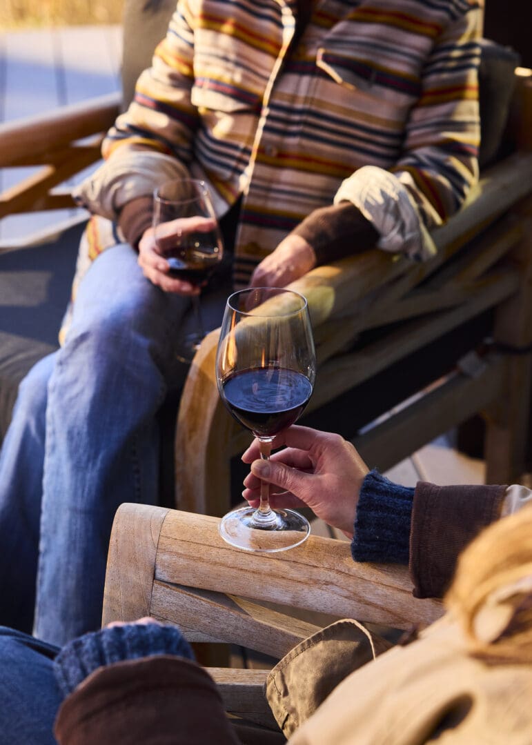 Low shot of women holding wine in their hands while sitting in chairs.
